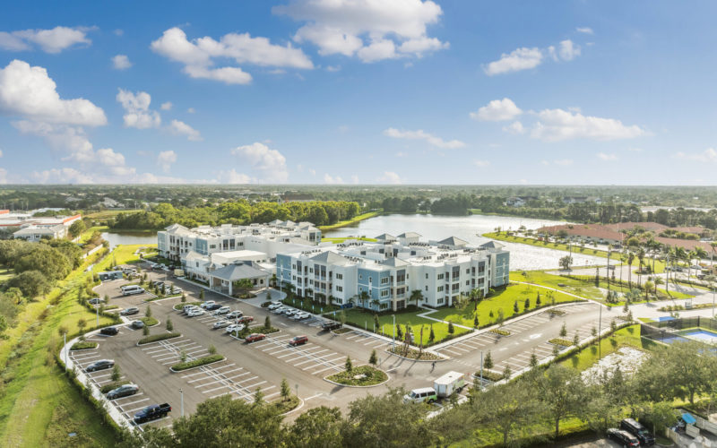 Aerial view of Aviva Port St. Lucie showing the residential buildings surrounded by landscaped grounds and a serene lake.