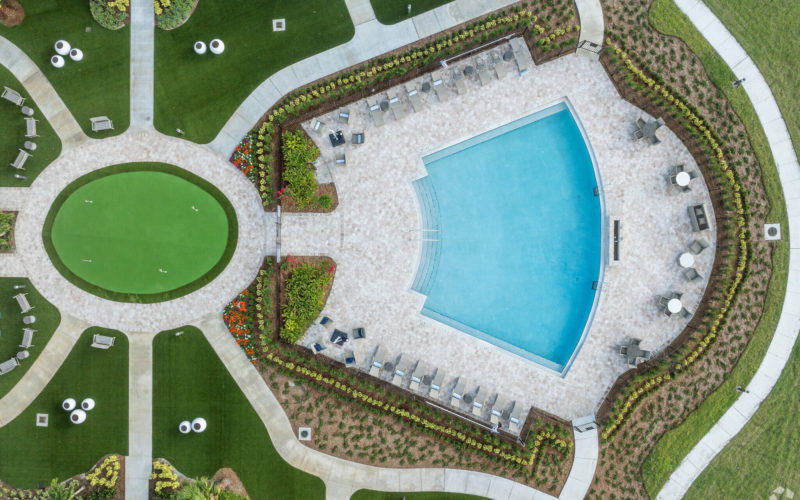 Resort-style pool at Aviva Port St. Lucie with spacious lounging areas, umbrellas, and landscaped surroundings.